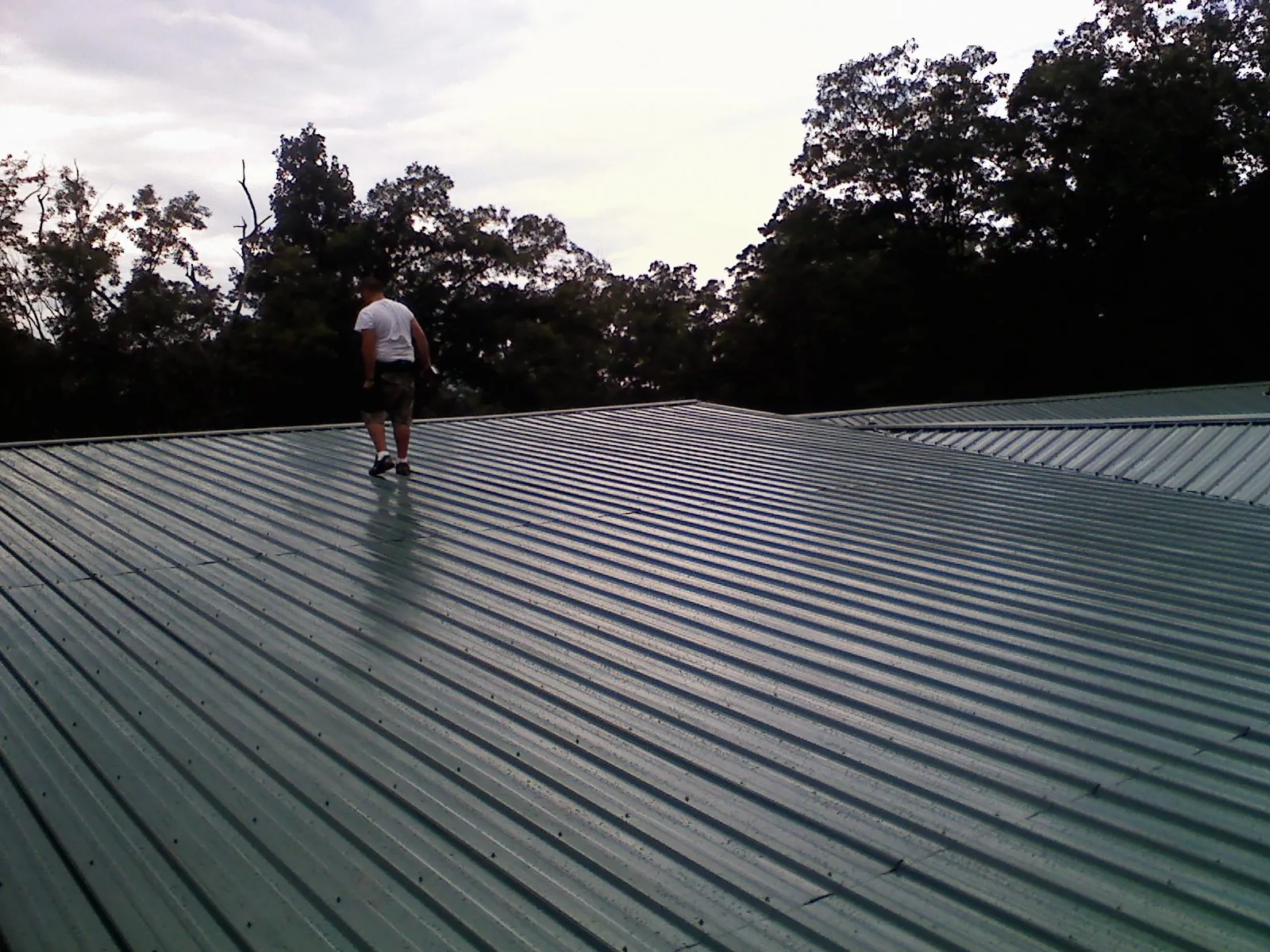 Roofer walking a wide expanse of new green metal roofing in Newburg