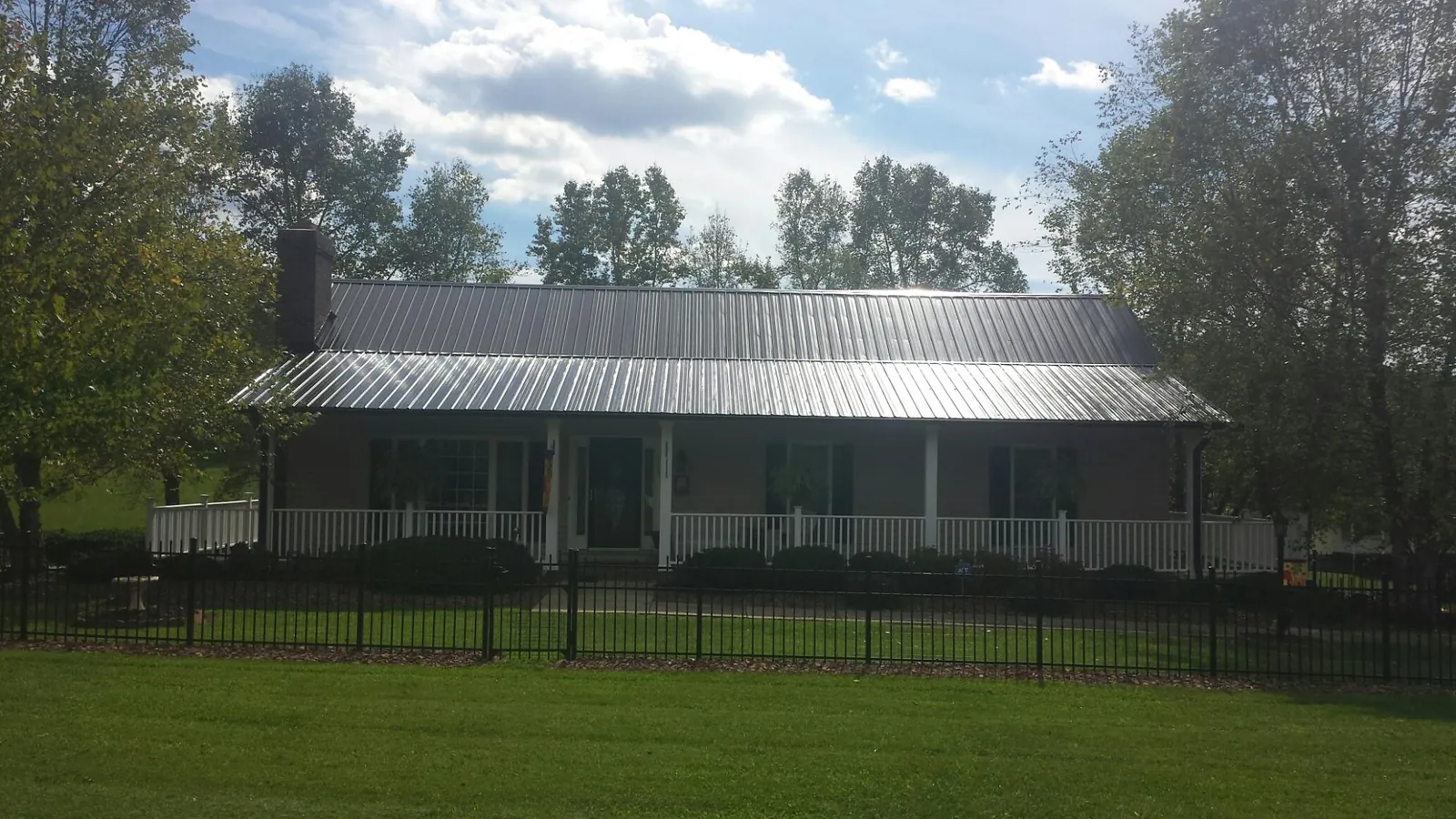Gray metal roof on a brick ranch with a full width front porch — Gutter Guard Installation work by our crew in Newburg